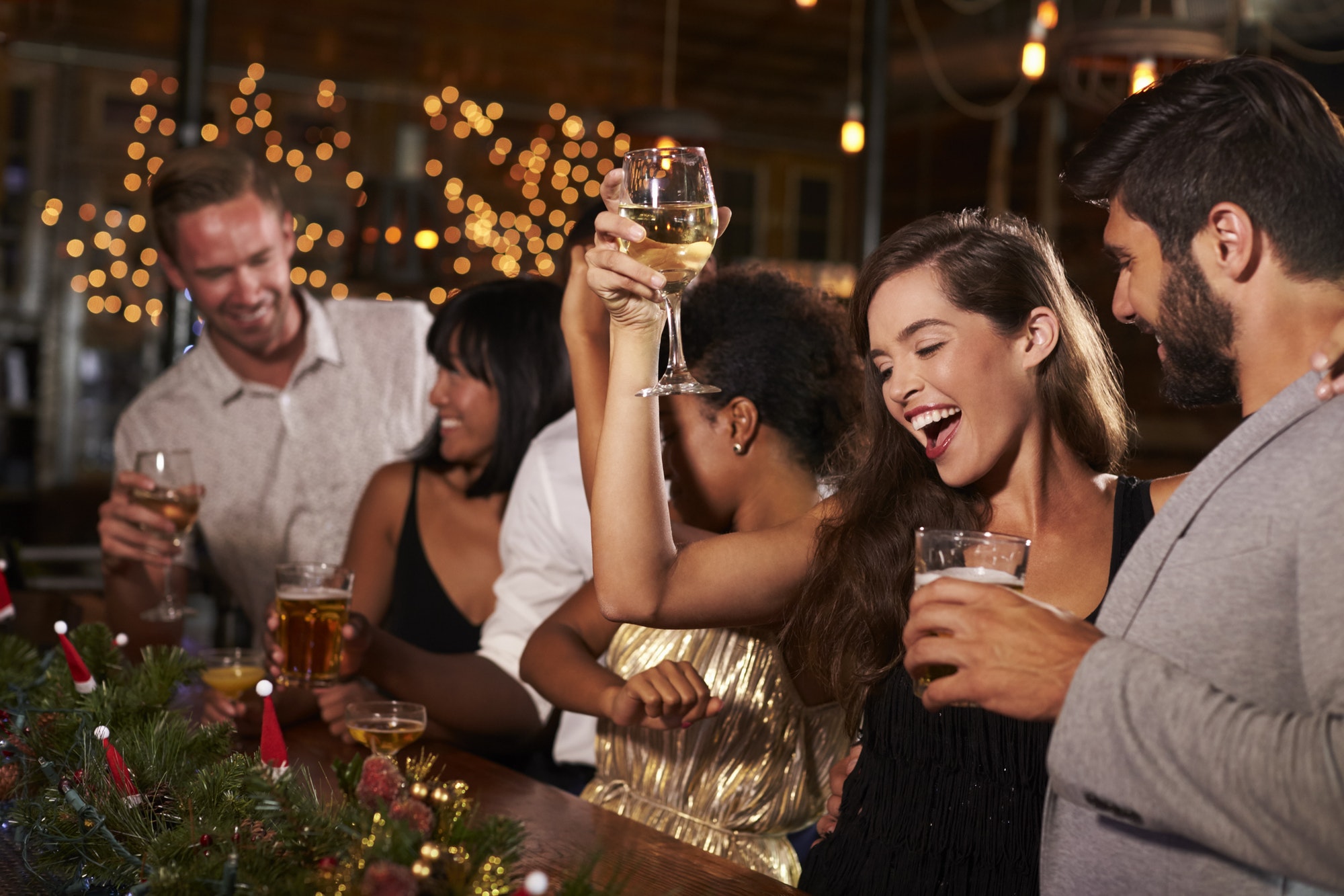Woman raising a glass at a Christmas party in a bar