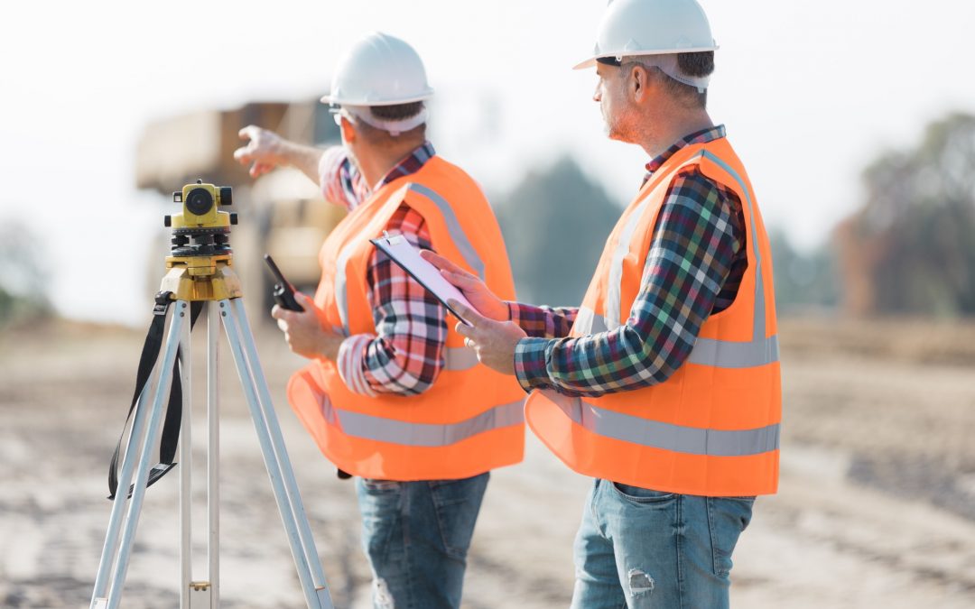 Two road construction workers using measuring device on the field